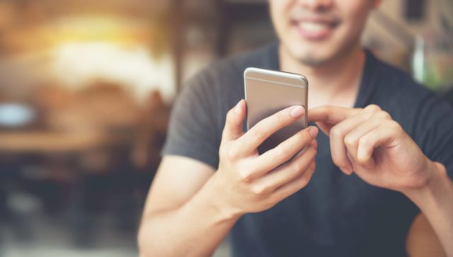 man sitting down scrolling on his phone