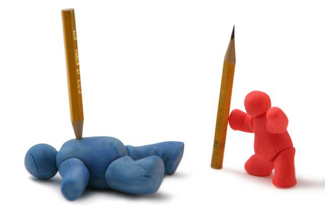 Clay figure in red pushing a pencil towards a blue clay figure lying flat with a pencil through it, symbolising conflict or defeat