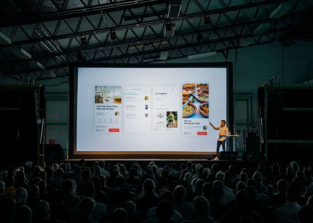 people in chairs watching presentation on big screen