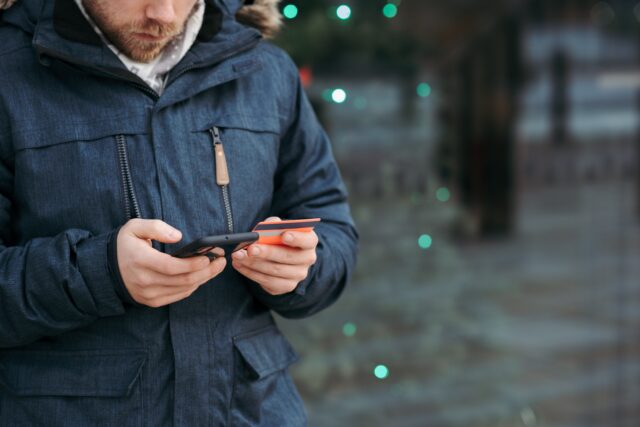 man using his phone and credit card for streamlined payment