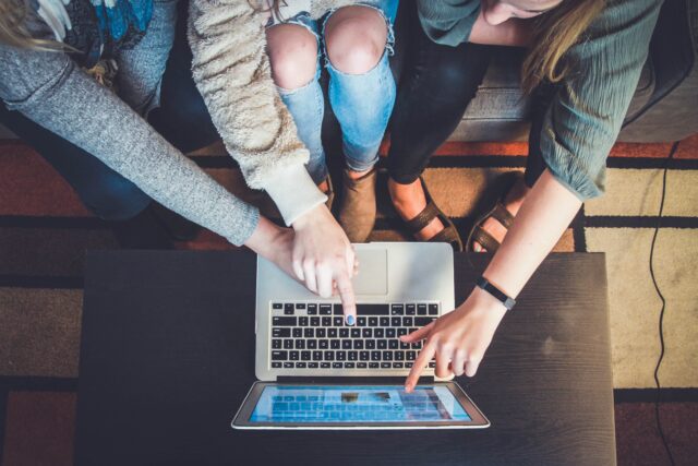 People pointing at a laptop screen, presumably at a product/service they like