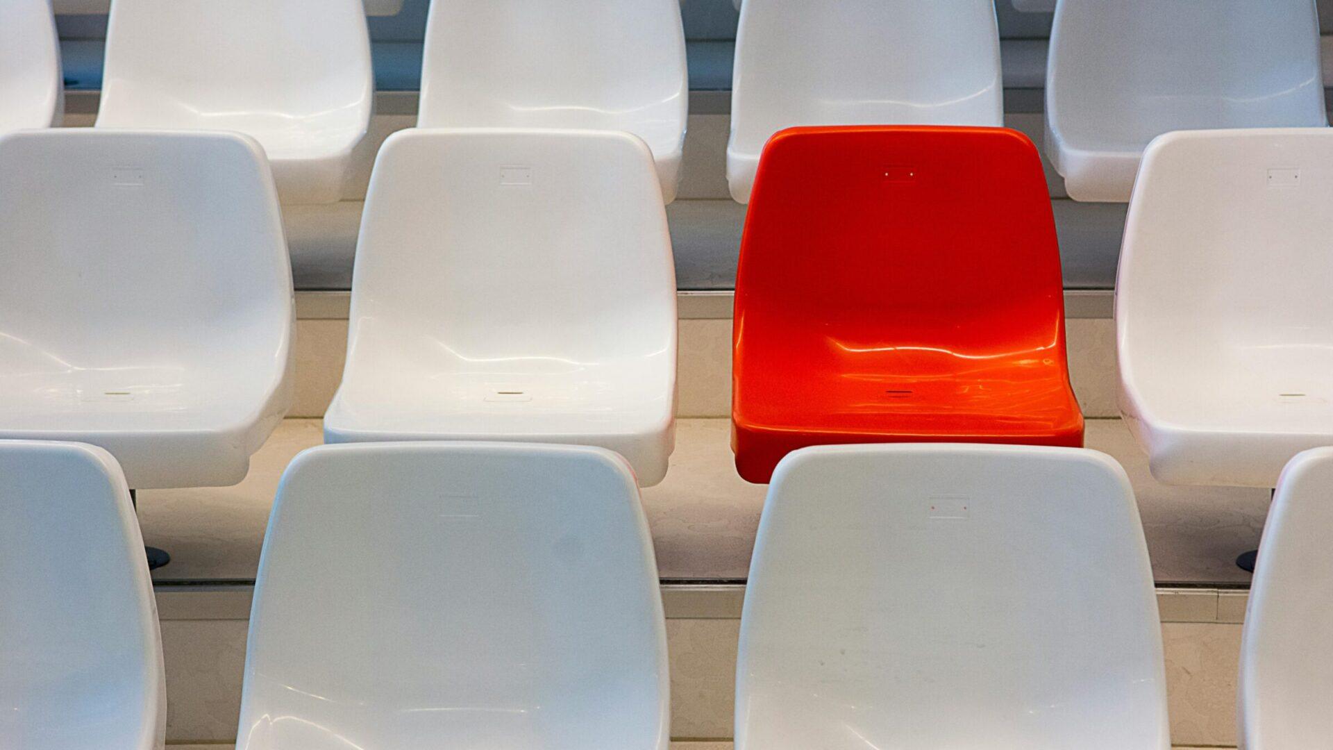 Red seat amongst a row of white seats