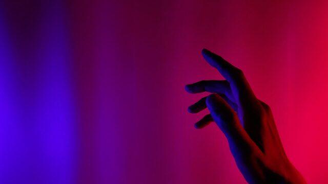 Hand raised against abstract blue/red background