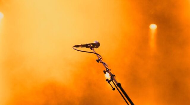 A microphone on a stand illuminated by a bright orange spotlight, representing Digital PR stepping into the limelight as a core SEO strategy.