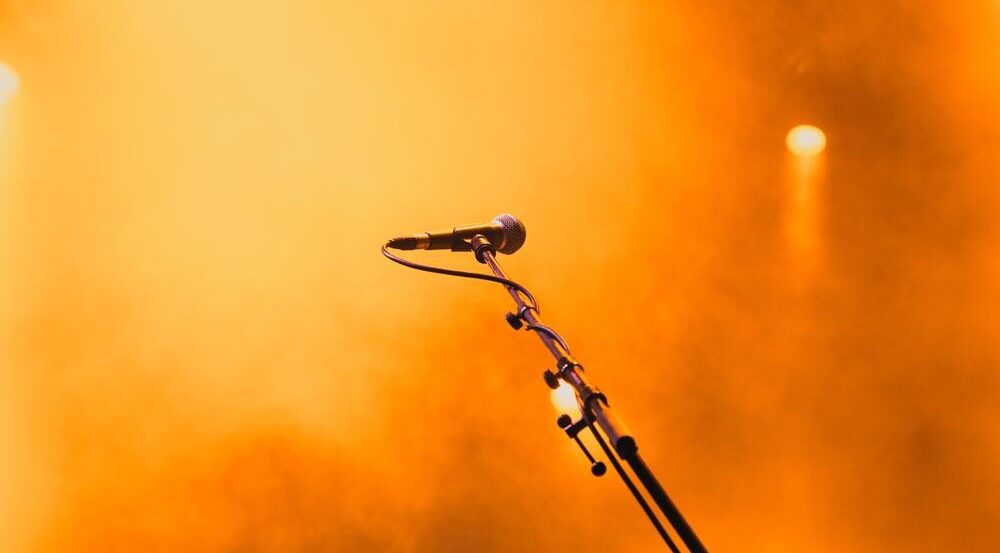 A microphone on a stand illuminated by a bright orange spotlight, representing Digital PR stepping into the limelight as a core SEO strategy.