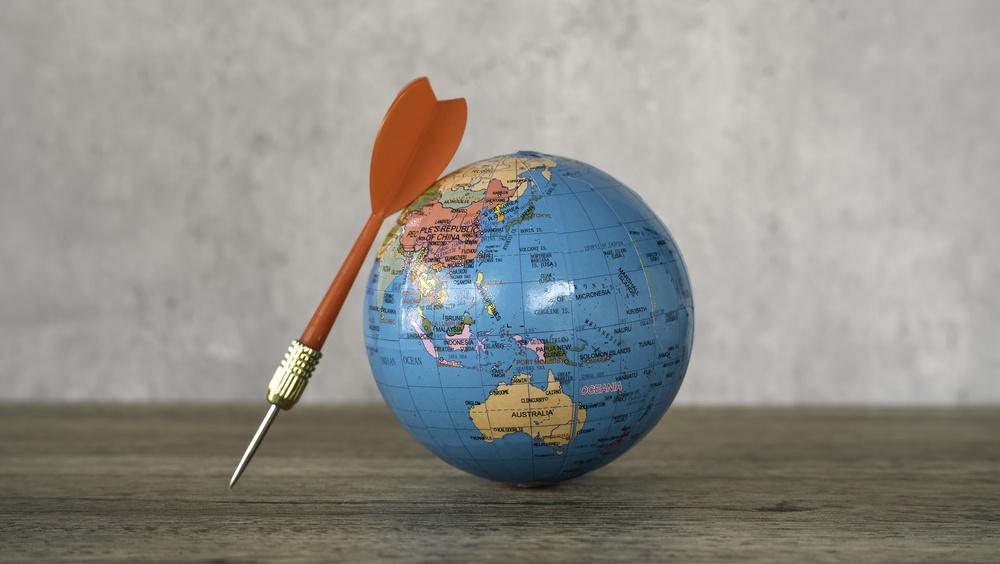 Red,Dart,Placed,Beside,A,Small,World,Globe,,Representing,Global